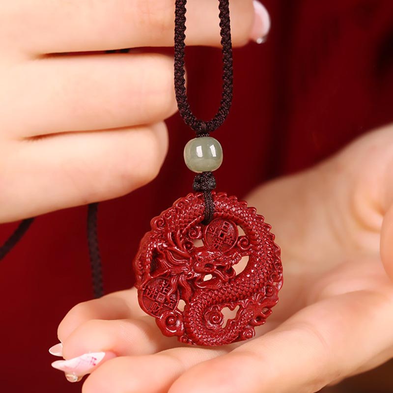 Cinnabar Hetian Jade Dragon Necklace - red dragon amulet in manicured hand, burgundy backdrop