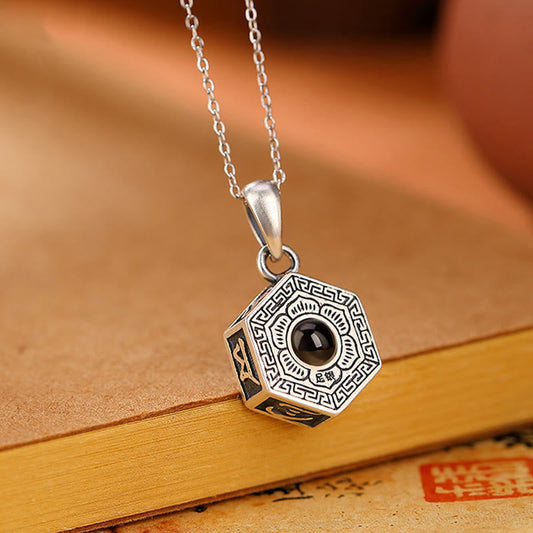 Sterling Silver Mantra Necklace – Three-quarter view of hexagonal pendant with onyx cabochon on antique manuscript