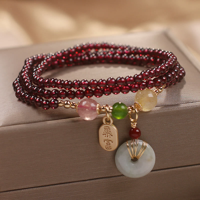 Garnet wrap bracelet with zhao cai attract wealth gold plaque tag and white jade ping an kou safety buckle disc pendant with gold wire wrap on taupe jewelry box