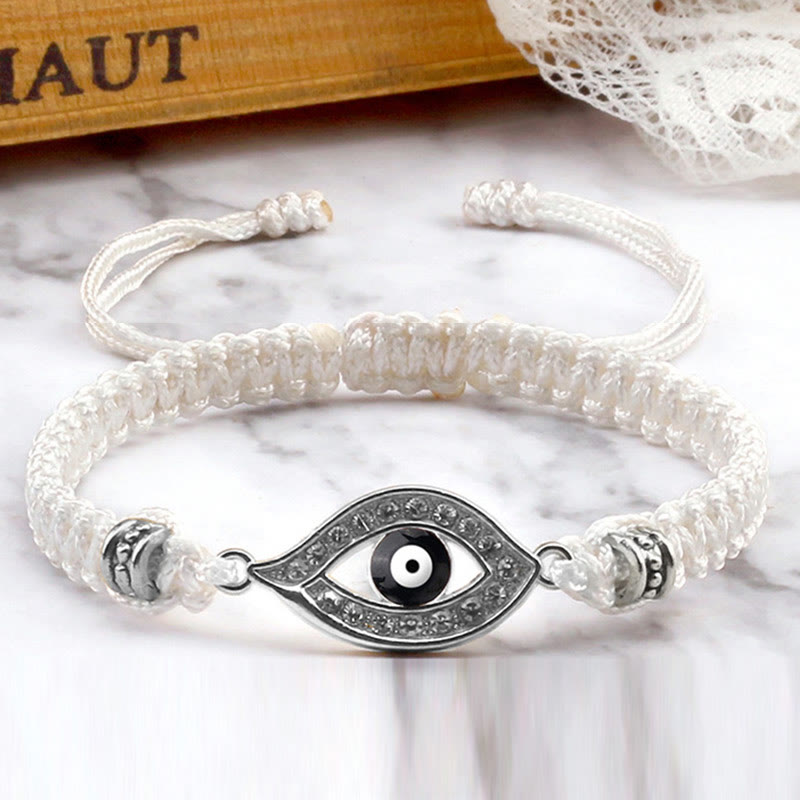 White cord evil eye bracelet with silver crystal pave charm, marble lifestyle photo