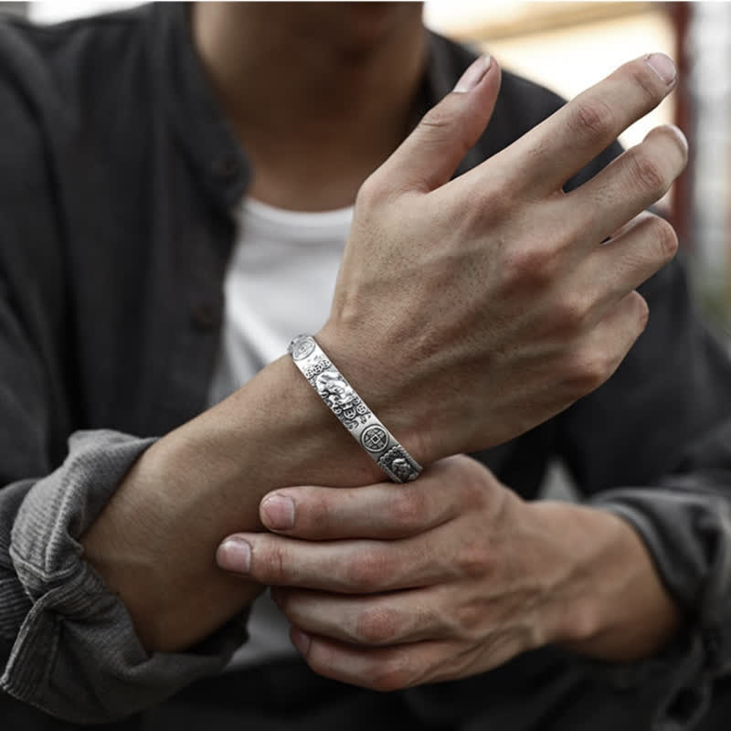 Silver Pixiu wealth bracelet worn on man's wrist, oxidized finish with engraved Chinese motifs, feng shui protection jewelry for men
