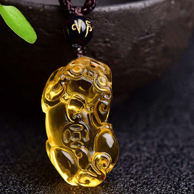 Citrine PiXiu Necklace Pendant – Front view of citrine PiXiu hanging near ceramic bowl with leaf, wealth