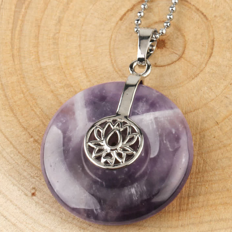 Crystal Amethyst Pink Crystal Lotus Necklace – Purple amethyst donut pendant with lotus overlay on wood, close-up spiritual jewelry