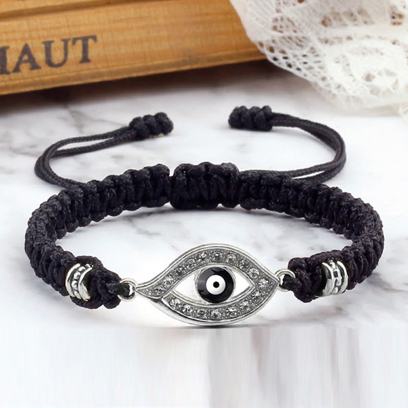 Black cord evil eye bracelet with silver crystal evil eye charm, marble lifestyle photo