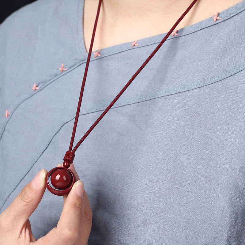 Cinnabar PiXiu Necklace – Model in light gray top holding pendant, casual wear style, feng shui pendant