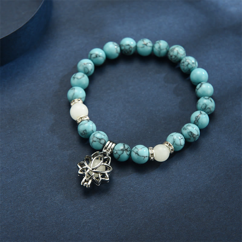 Tibetan Turquoise Glowstone Lotus Bracelet – turquoise howlite beads with white accents on dark blue-gray surface, lotus charm