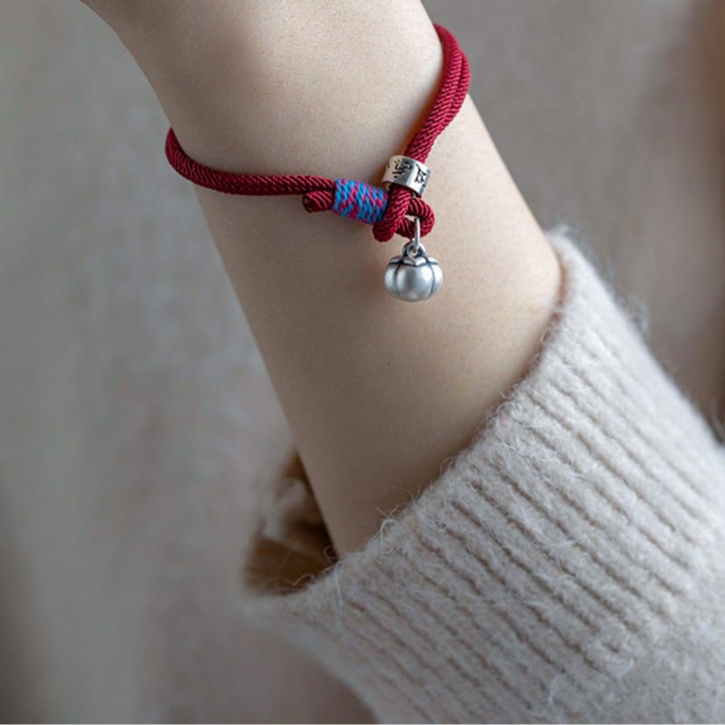 Om Mani Padme Hum Bracelet - Red cord worn on model wrist with silver persimmon charm, everyday spiritual bracelet