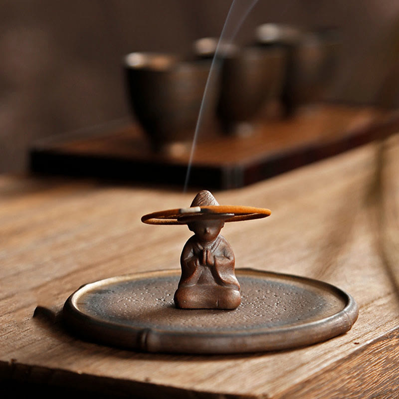 Brown monk figure with stick incense on bamboo ceramic dish, mindful