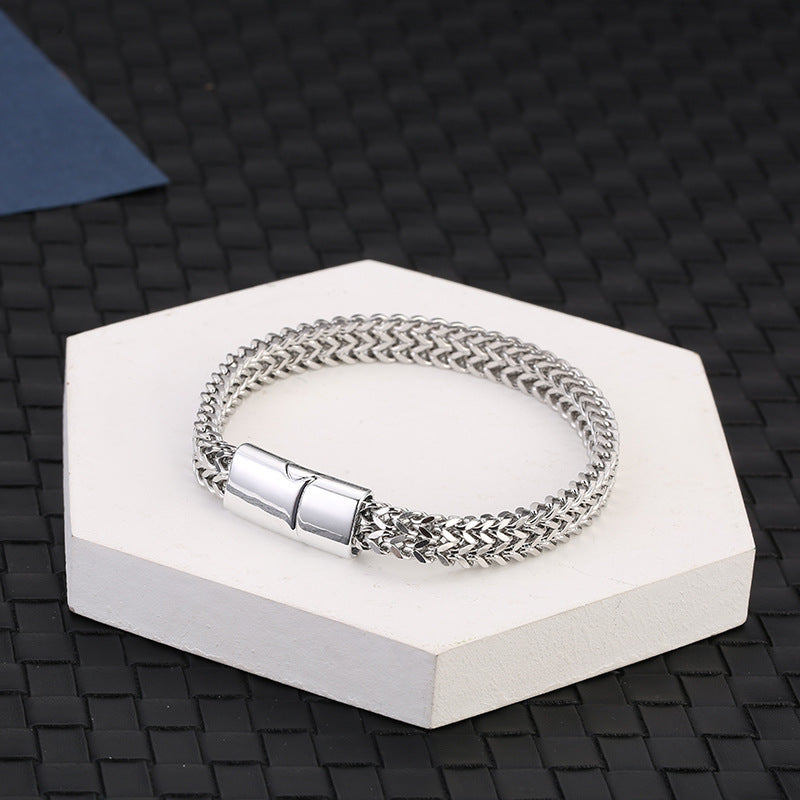 Fish Scale Titanium Steel Magnetic Bracelet – silver chain on white hexagonal pedestal, dark woven mat background, elevated angle