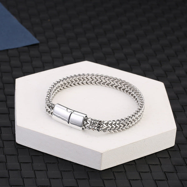 Fish Scale Titanium Steel Magnetic Bracelet – silver chain on white hexagonal pedestal, dark woven mat background, elevated angle