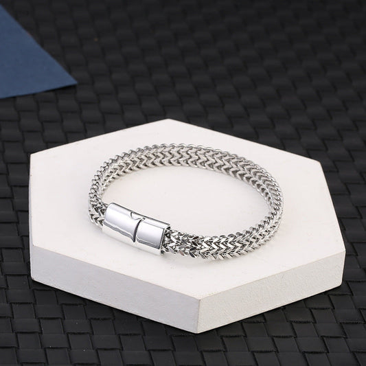 Fish Scale Titanium Steel Magnetic Bracelet – silver chain on white hexagonal pedestal, dark woven mat background, elevated angle