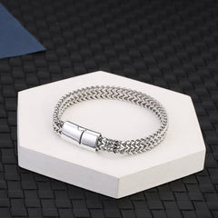 Fish Scale Titanium Steel Magnetic Bracelet – silver chain on white hexagonal pedestal, dark woven mat background, elevated angle