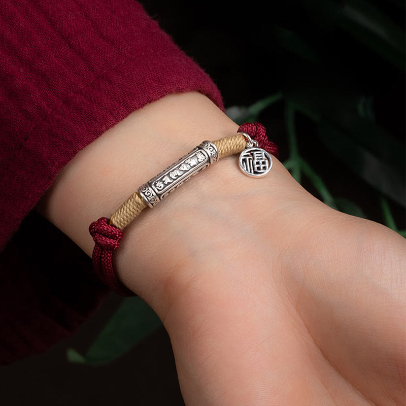 Adjustable black cord bracelet with antique silver Tibetan mantra tube bead, natural hemp wrapping and Chinese fortune blessing charm on brown background