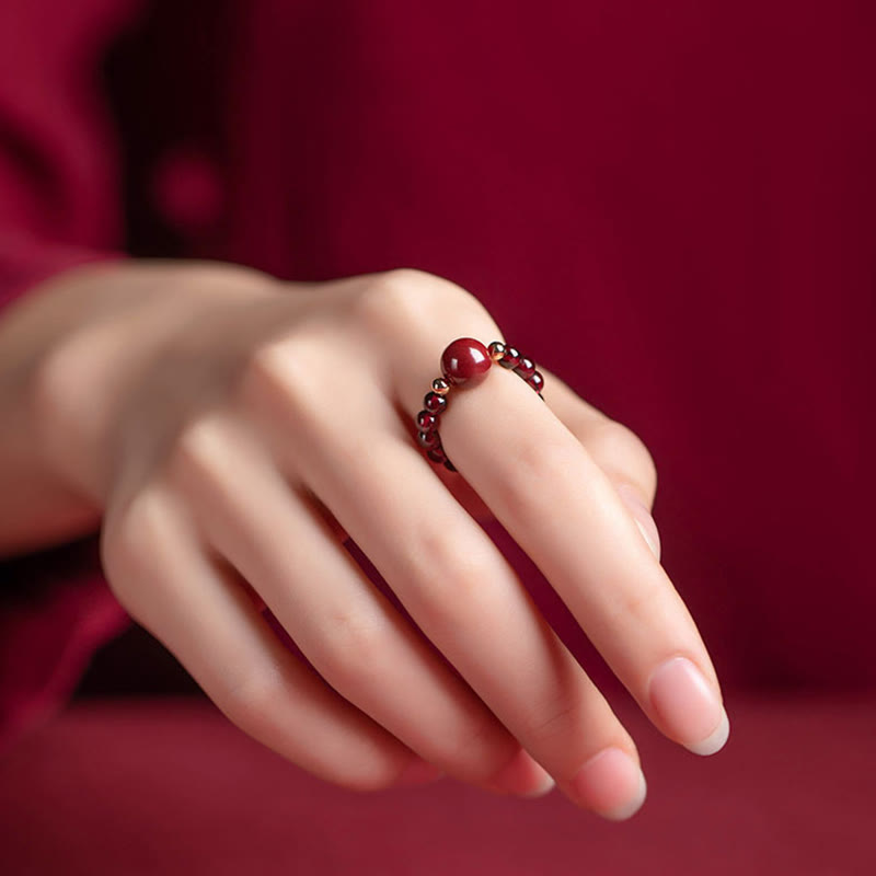 Garnet Cinnabar Ring – model hand cinnabar bead ring side angle red fabric, good luck talisman