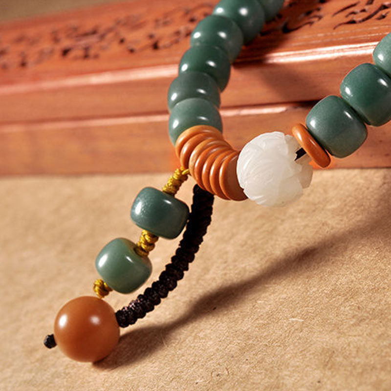 Lotus Cyan Bodhi Seed Bracelet - green rondelle beads with carved lotus focal and carnelian dangle, macro detail shot
