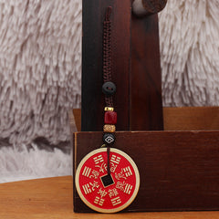 Shan Gui Keychain – bagua trigram design facing front, hanging on dark wood rack, auspicious cord