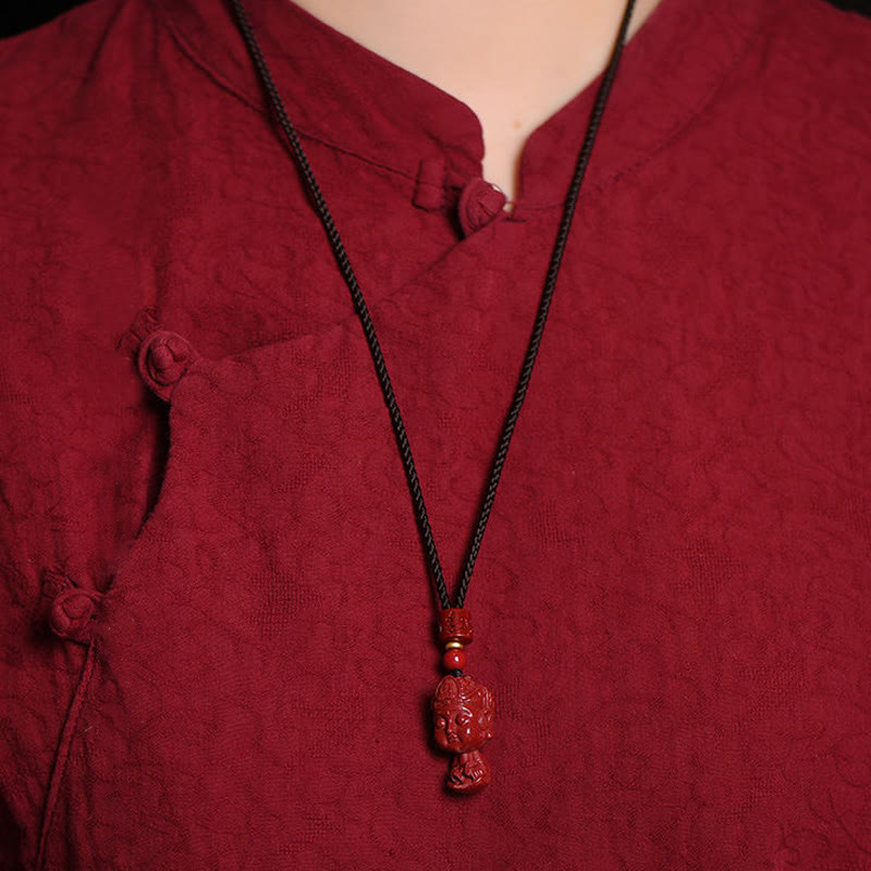 Chinese Zodiac Cinnabar Pendant – Worn against traditional burgundy garment, warm lighting, zodiac jewelry