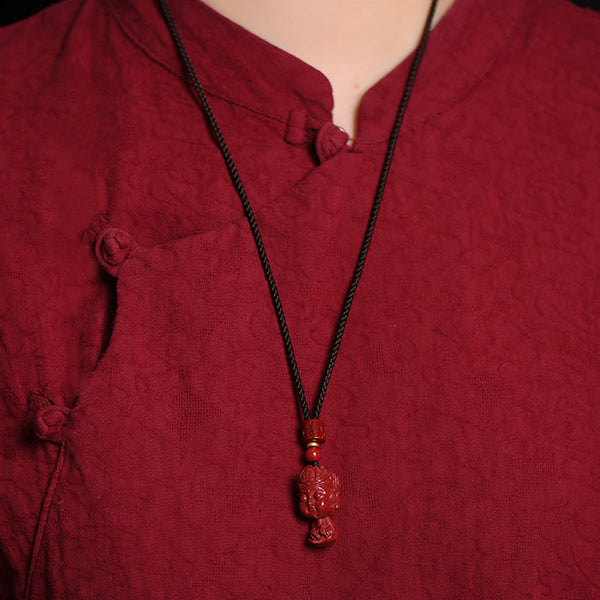 Chinese Zodiac Cinnabar Pendant – Worn against traditional burgundy garment, warm lighting, zodiac jewelry