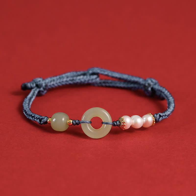 Hetian Jade Pearl Peace Buckle Bracelet – navy blue cord with jade disc pearls and gold spacers, red background frontal view