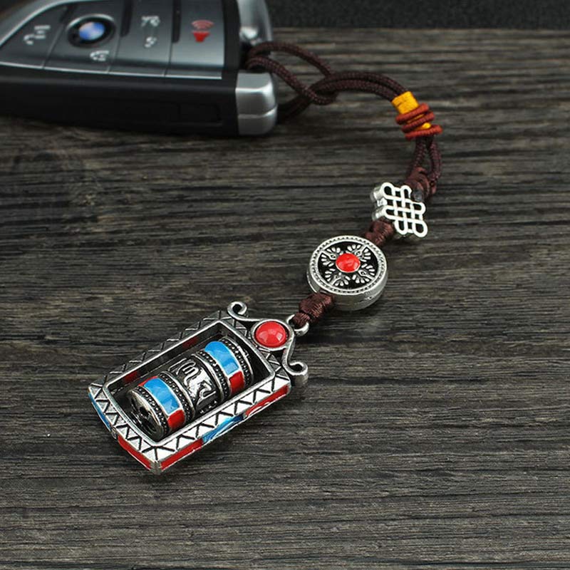 Om Mani Padme Hum Prayer Wheel Keychain – Angled on dark wood with car key, scale demonstration, Tibetan blessing keychain
