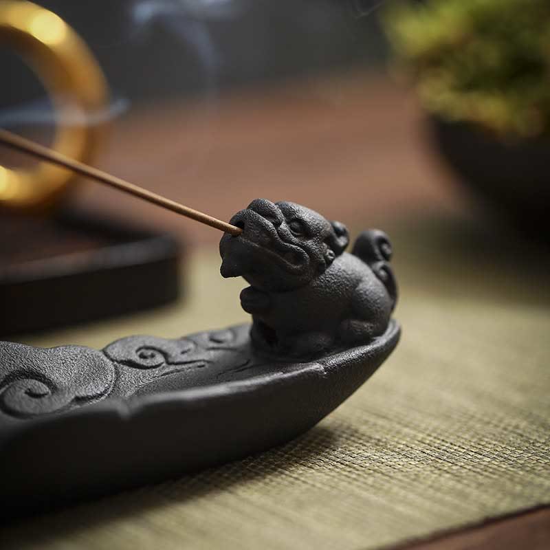 Extreme close-up of Pixiu beast face with incense smoke, golden bokeh, carved cloud base – dark ceramic incense burner detail