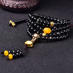 Black Obsidian Lotus Mala Bracelet - Low angle on charcoal with wood prop, gold stupa guru bead, obsidian