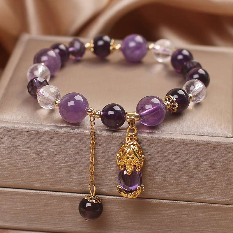Natural Amethyst PiXiu Healing Bracelet – purple and clear crystal beads with gold PiXiu pendant on jewelry box, copper healing unisex accessory