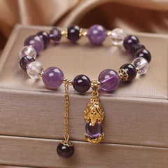 Natural Amethyst PiXiu Healing Bracelet – purple and clear crystal beads with gold PiXiu pendant on jewelry box, copper healing unisex accessory
