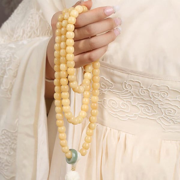 Bodhi Seed Lotus Dzi Bracelet - Cream bodhi strands draped through fingers on embroidered hanfu, prayer beads