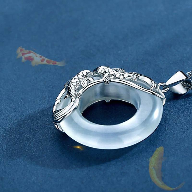 Elegant silver koi fish necklace featuring white jade donut pendant in ornate setting with detailed fish sculpture, koi pond background