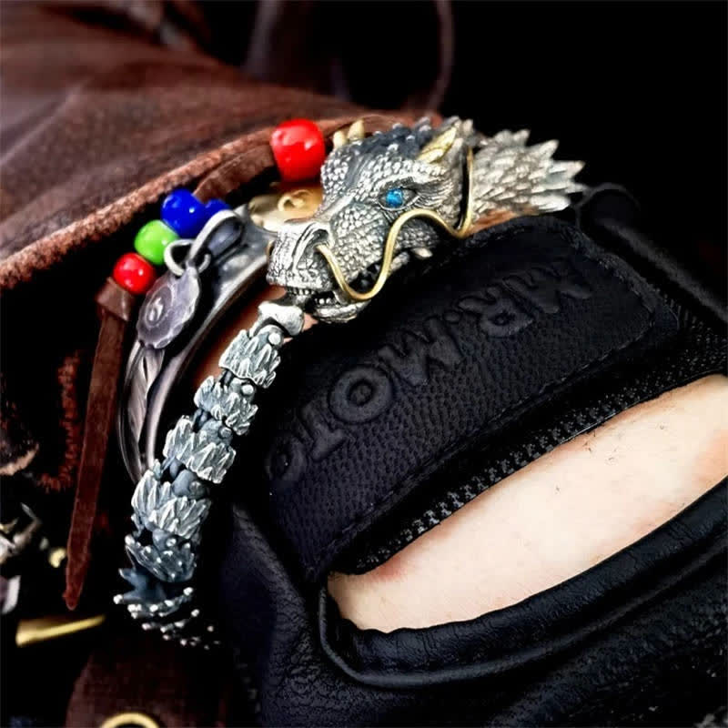Dragon cuff bracelet worn on wrist with black leather glove featuring dragon head with blue eyes gold whiskers scale body and colorful bead accents near clasp