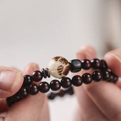 Red Sandalwood Lotus Bodhi Seed Bracelet – Handheld dark wood beads with carved cream lotus center, soft bokeh background