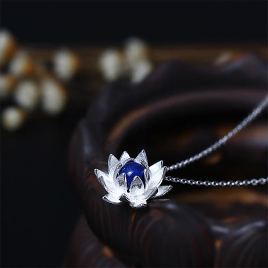 Lapis Lazuli Lotus Necklace - silver lotus pendant with deep blue lapis center on dark wood, lapis necklace