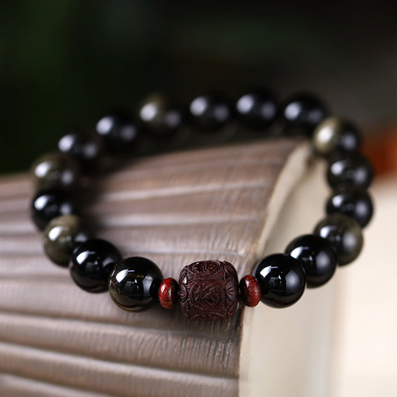 Gold Sheen & Rainbow Obsidian Fu Bracelet – draped on open book with carved center, healing jewelry