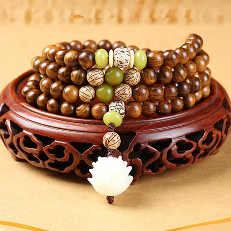 Rosewood Lotus Mala – coiled on carved wooden stand with jade accents and lotus charm, inner calm