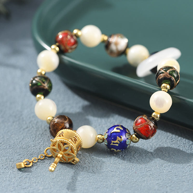 Liuli Glass Prayer Wheel Bracelet – Close-up of gold prayer wheel charm with mantra engraving