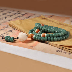 Lotus Cyan Bodhi Seed Bracelet - sage green coiled mala with lotus pendant on vintage calligraphy paper, cultural flat lay