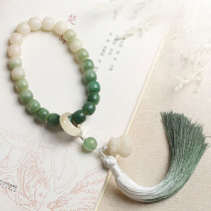 Bodhi Seed Lotus Wisdom Wrist Mala – Full bracelet flat lay with lotus charm and green ombre tassel on book, running ring detail