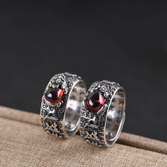 Feng Shui PiXiu Ring – Pair of silver rings with red stones on burlap against dark backdrop