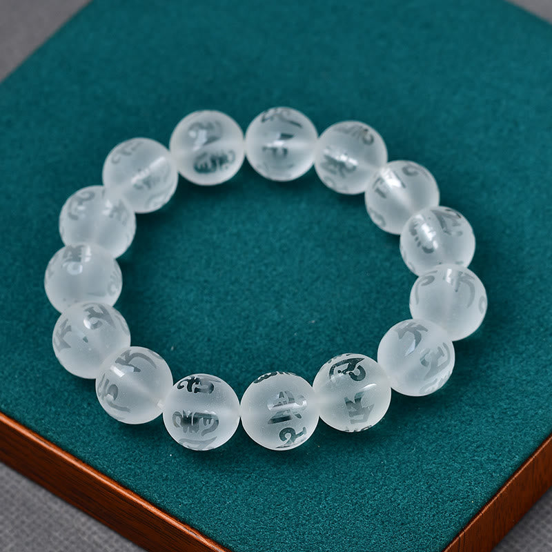 White Crystal Mantra Bracelet – Etched mantra beads on teal velvet jewelry display pad Imagen principal del producto