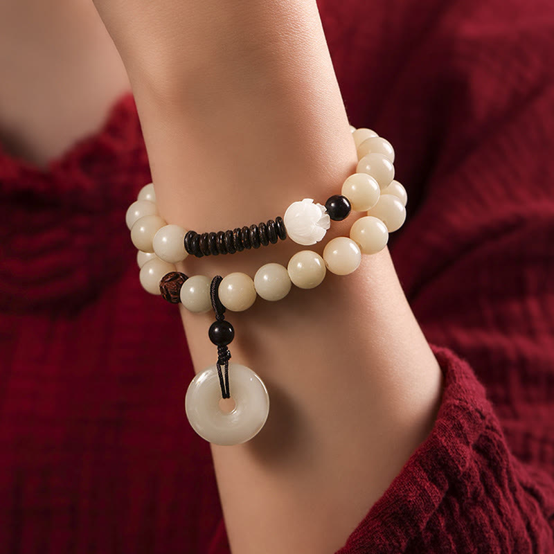 Bodhi Seed Sandalwood Lotus Bracelet - wrist close-up with hand adjusting, wood and jade contrast, elegant