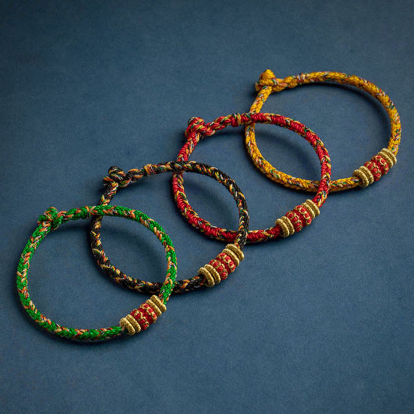 Set of four handmade braided cord bracelets in green black red and yellow with gold beads and red decorative bands, adjustable traditional Tibetan lucky rope jewelry