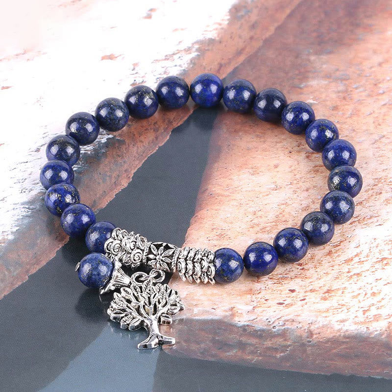 Tree of Life lapis lazuli bracelet with deep blue beads featuring gold pyrite inclusions, ornate silver metal spacers and tree of life charm.