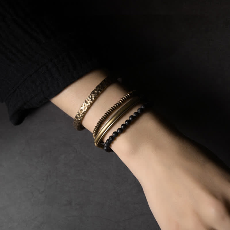Lava Rock Copper Healing Bracelet – Black porous lava beads with copper cage focal bead and silver spacers on dark stone surface, elevated side angle macro