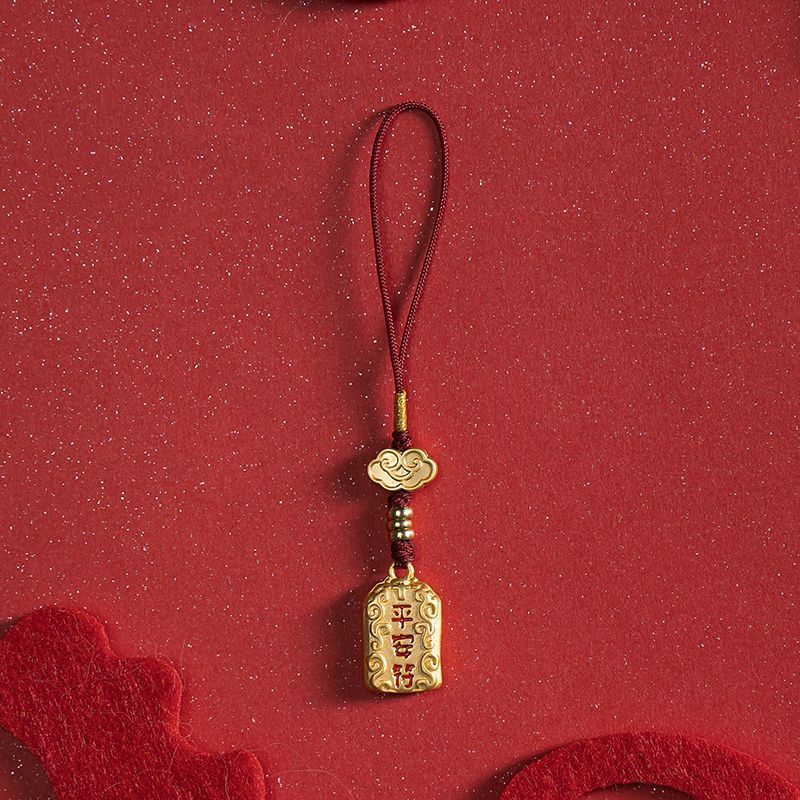 Single brass peace charm with red cord on red festive background