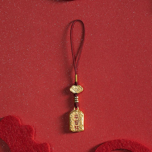 Single brass peace charm with red cord on red festive background