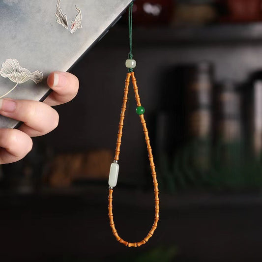 Olive Kernel Phone Chain – hand holding koi-pattern phone with olive bead strap in dark Chinese-style setting, zen phone accessory