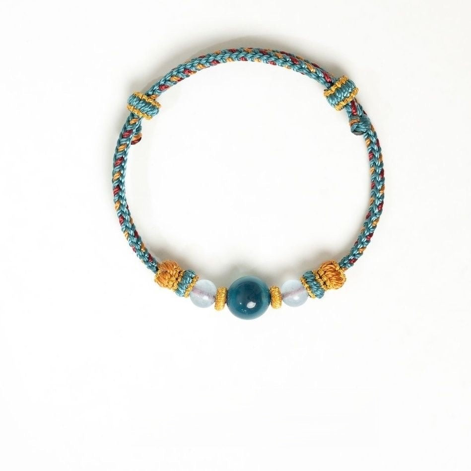 Dunhuang Agate Bracelet – turquoise woven bracelet with dark aqua center and milky white beads flat lay on white, adjustable cord bracelet