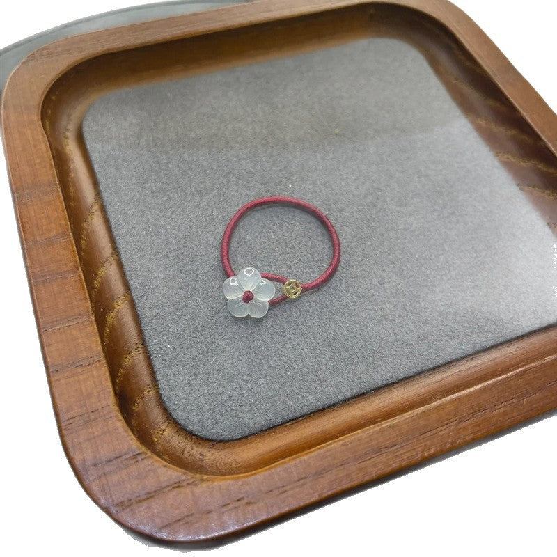 Red String Flower Ring – red cord ring with white flower on wooden tray with gray felt lining, artisan display, feng shui gift