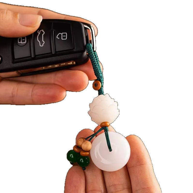 Chalcedony Lotus Keychain – hand holding black car key with lotus peace buckle charm on white, womens amulet